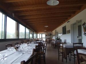 a dining room with tables and chairs and windows at Agriturismo Locoe in Oliena
