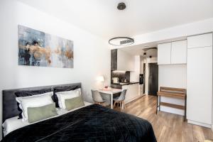 a bedroom with a bed and a table and a kitchen at Super-Apartamenty Plac Wolności 6 in Poznań