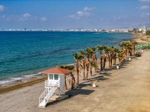 a beach with palm trees and a lifeguard house at Sunny Villa with Hot Tub, Garden and 2 Bedrooms, 5 Minutes to the Beach in Pyla