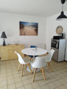 a kitchen with a table and white chairs and a table at Maison de vacances en Bretagne à 900 m de la plage - 5 personnes - Piscine chauffée in Erdeven
