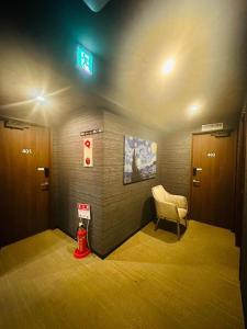 una sala de espera con una silla y una boca de incendios en ehostel心斎橋 2人ROOM, en Osaka