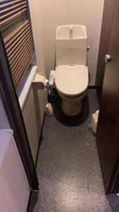 Un baño con un inodoro blanco en una cabina. en ehostel心斎橋 2人ROOM, en Osaka 2 fotos más