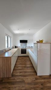 cocina con armarios blancos y suelo de madera en Apartmán VIVINO, en Bojnice