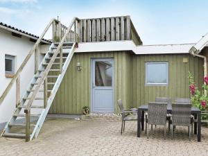 a green house with a wooden staircase and a table and chairs at 6 person holiday home in Lemvig-By Traum in Ferring