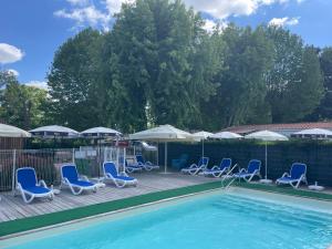 un gruppo di sedie e una piscina con ombrelloni di Mobil-home 2 chambres côté rivière a Ébreuil Altre 15 foto