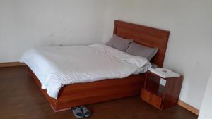 a bed with a wooden headboard and a night stand at Sport Guest House in Addis Ababa