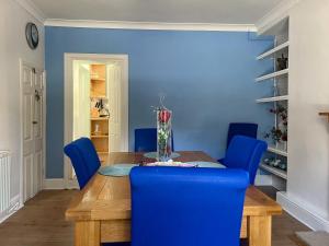 ein Esszimmer mit blauen Wänden und einem Holztisch und blauen Stühlen in der Unterkunft Gwenynen Fel Cottage in Burry Port
