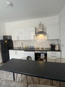 eine Küche mit weißen Schränken und einem Tisch mit Stühlen in der Unterkunft The Bake Apartment - 5 bedroom Large Apartment sleeps up to 16 person in Newcastle upon Tyne