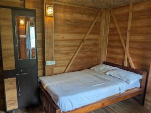 a bed in a room with a wooden wall at Ashokavanam Heritage Village by N Square in Kanthalloor