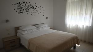 a bedroom with a bed with white sheets and birds on the wall at Apartmani Sanja in Vrsi