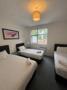ein Zimmer mit drei Betten und einem Fenster in der Unterkunft The Bake Apartment - 5 bedroom Large Apartment sleeps up to 16 person in Newcastle upon Tyne