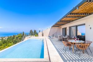 a villa with a swimming pool and a table and chairs at Villa Andromeda Sunset in Tsoukalades