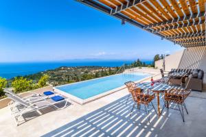 a patio with a table and chairs next to a swimming pool at Villa Andromeda Sunset in Tsoukaladhes