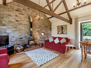 a living room with a red couch and a stone wall at 1 Bed in Bude WBARN in Sutcombe