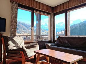 a living room with a couch and a table and windows at Appartement lumineux au ski pour 6 - Grand balcon, cœur du village - FR-1-458-96 in Le Grand-Bornand
