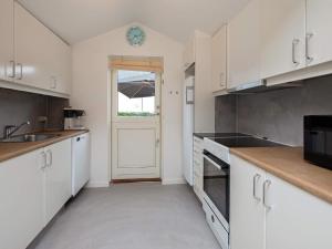 a kitchen with white cabinets and a white door at 6 person holiday home in Væggerløse in Bøtø By
