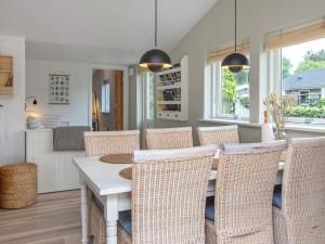 a dining room with a white table and wicker chairs at 6 person holiday home in Væggerløse in Bøtø By