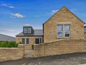 une maison en briques avec un mur en pierre devant elle dans l'établissement Oakwood Lodge, à Matlock
