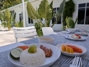 a table with plates of rice and fruit on it at Avi Guesthouse in Thoddoo