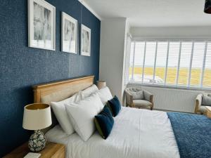 a bedroom with a large bed with blue walls at Large villa opposite beach in Great Yarnouth in Great Yarmouth