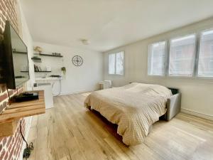 een slaapkamer met een bed, een bureau en ramen bij Grand T2 au RDC hyper centre Navette et Sauna en option in Beauvais