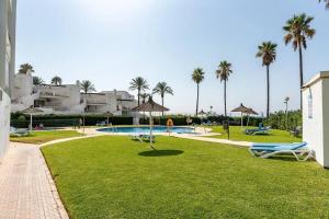 a resort with a swimming pool and palm trees at Apartment beachside in Calahonda in Cabopino