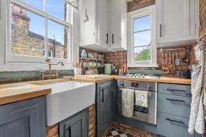 a kitchen with blue cabinets and a sink at Charming London with balcony in London +18 photos
