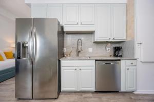 a kitchen with a stainless steel refrigerator and white cabinets at Phoenix II 2151 condo in Romar Beach +65 photos