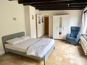 a bedroom with a bed and a blue chair at Duinland 142 in Sint Maartensvlotbrug
