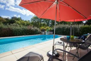 a table with an umbrella next to a swimming pool at La Garenne avec sa piscine privée proche de Sarlat in Saint-Crépin-et-Carlucet