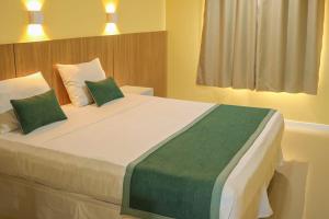 a bedroom with a large bed with green and white pillows at Maren Praia Hotel in São Luís +11 photos