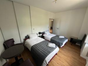 a hotel room with two beds and a table at Charmant appartement RDC familial ou pour le travail in Uzerche