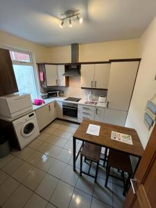 een keuken met een tafel, een fornuis en een magnetron bij Tower St Cranes Murals Titanic 3br-6guests in Belfast