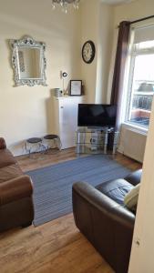 een woonkamer met een bank en een televisie bij Tower St Cranes Murals Titanic 3br-6guests in Belfast