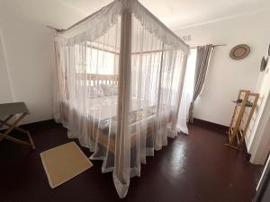 une chambre avec un lit à baldaquin avec des rideaux blancs dans l'établissement John's Place, à Arusha