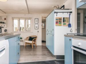 a kitchen with blue and white cabinets and a chair at 5 person holiday home in Hemmet-By Traum in Falen