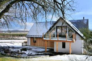 una piccola casa con neve sul tetto di Beautiful Lodge with hot tub & panoramic views a Boat of Garten