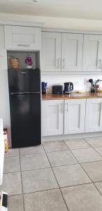 a kitchen with a black refrigerator and white cabinets at Electric Picnic Accommodation in Stradbally