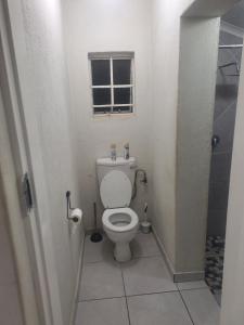 a small bathroom with a toilet and a window at Bella Cottage Escape in Rooihuiskraal