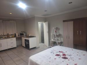 a bedroom with a bed and a kitchen with a stove at Bella Cottage Escape in Rooihuiskraal