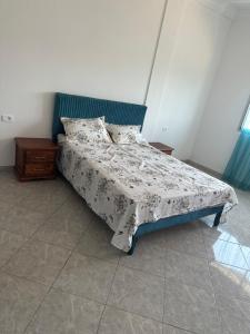 a bedroom with a bed with a blue headboard at Liliane Appartement in El Haouaria