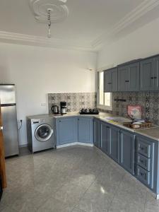 a kitchen with blue cabinets and a washing machine at Liliane Appartement in El Haouaria