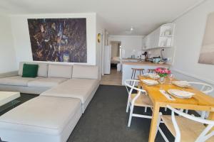 a living room with a white couch and a table at Coastal Scarborough Beach Chic Pool View 2BR in Perth