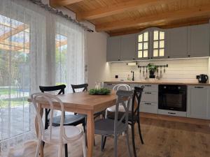 a kitchen with a wooden dining table and chairs at "Źródło zasilania" domki letniskowe nad Zalewem Chańcza in Raków