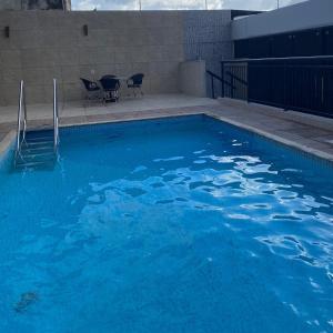a large blue swimming pool with two chairs in it at Edifício Montpellier in Curro Velho