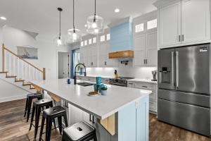 a kitchen with white cabinets and a large island with bar stools at Salty Seabass 4BR Seaside Escape in Port Bolivar