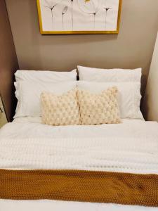 a bed with white sheets and pillows on it at Maison De Tabasa near Tops Cebu in Cebu City +40 photos
