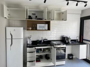 Una cocina con electrodomésticos blancos y un refrigerador blanco. en Flat na Liberdade próximo do Metrô, en São Paulo