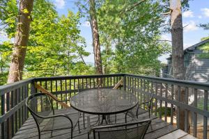 a table and chairs on a deck with trees at Cozy Retreat awaits w Pool Grill Near Dollywood in Pigeon Forge