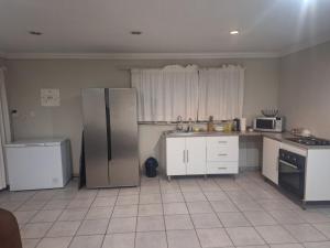 eine Küche mit einem Edelstahlkühlschrank und weißen Schränken in der Unterkunft Bella Cottage Escape in Centurion